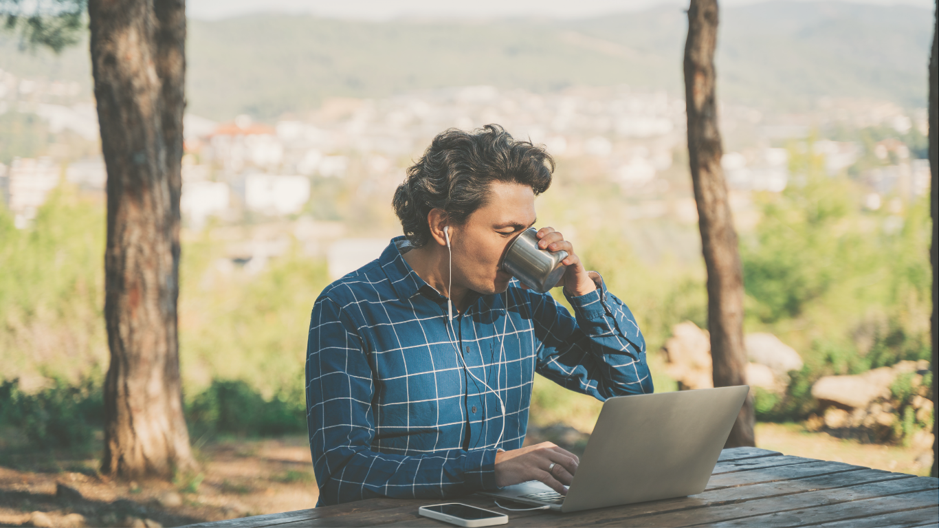 A man working on a laptop outside his camper van, combining digital nomad work with outdoor travel.